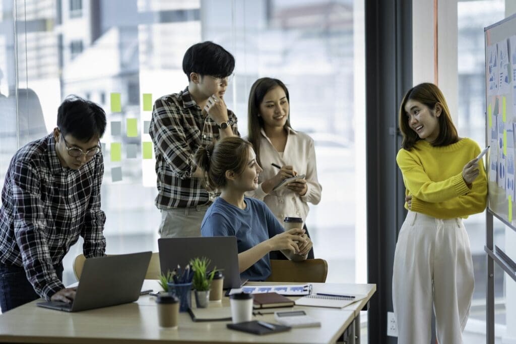 A group of young modern Asians in smart casual wear are having a brainstorming meeting while sitting